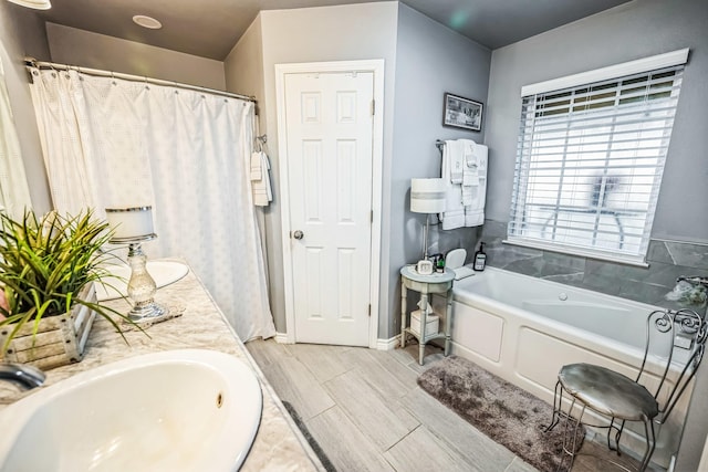 full bathroom featuring a garden tub, a sink, baseboards, wood tiled floor, and double vanity