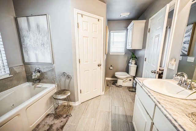 bathroom with a bath, vanity, toilet, and baseboards