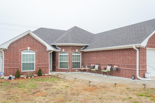 single story home with a shingled roof, a front lawn, and brick siding