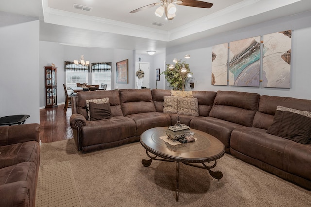 living room with ceiling fan with notable chandelier, visible vents, wood finished floors, and ornamental molding