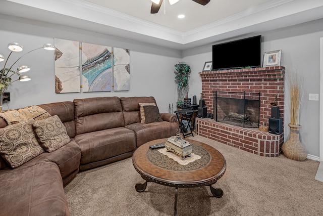 carpeted living area featuring recessed lighting, a raised ceiling, ornamental molding, a ceiling fan, and a brick fireplace