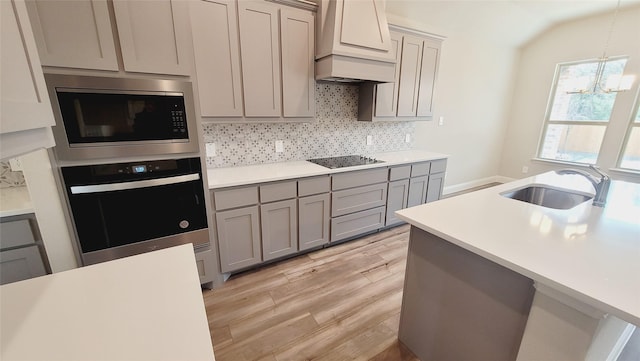 kitchen with light countertops, oven, a sink, and premium range hood