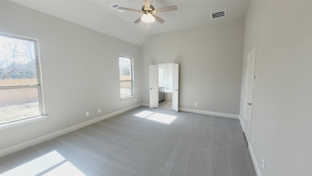 unfurnished bedroom featuring baseboards, visible vents, lofted ceiling, ensuite bath, and carpet floors