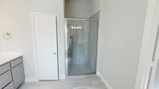 bathroom featuring a stall shower, baseboards, and vanity