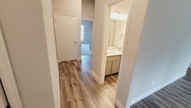 hall with baseboards and light wood-style floors