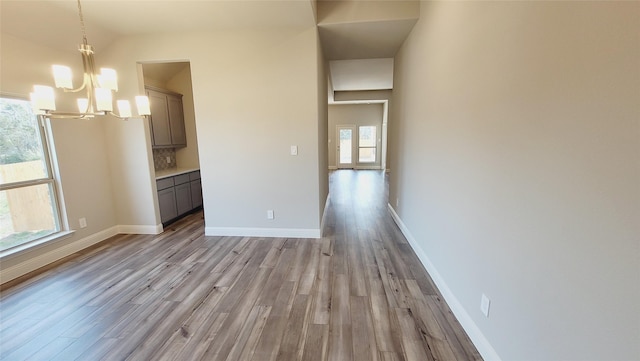 unfurnished dining area featuring baseboards, light wood-type flooring, and an inviting chandelier