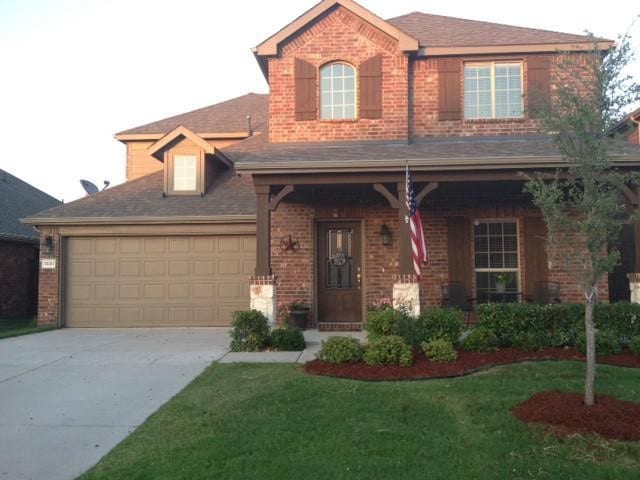 view of front of house featuring brick siding, concrete driveway, covered porch, a front yard, and a garage