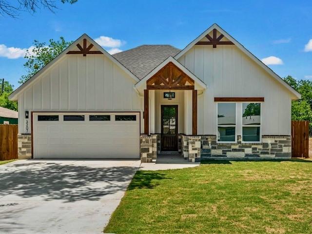 view of front of house with a garage, driveway, a front lawn, and fence