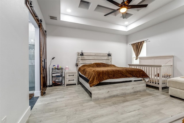 bedroom with recessed lighting, visible vents, a barn door, light wood-type flooring, and baseboards