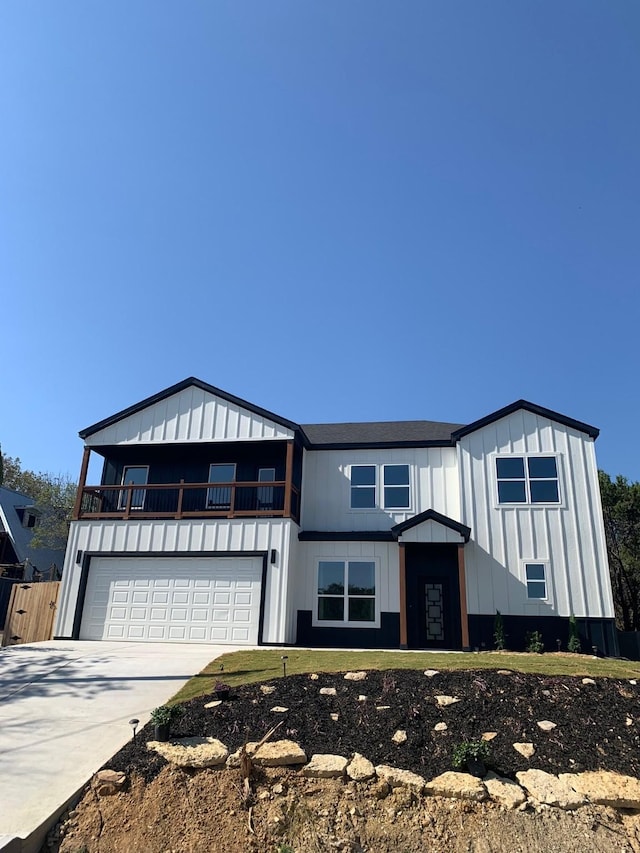 modern farmhouse featuring concrete driveway, a balcony, an attached garage, fence, and board and batten siding