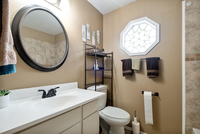 full bathroom featuring a textured wall, vanity, and toilet