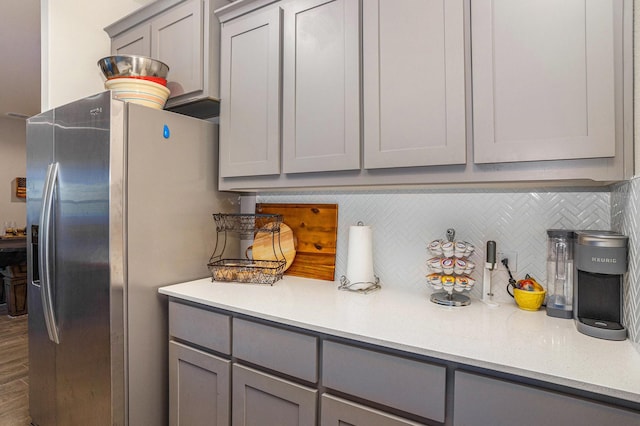 kitchen featuring gray cabinets, decorative backsplash, light countertops, and stainless steel refrigerator with ice dispenser