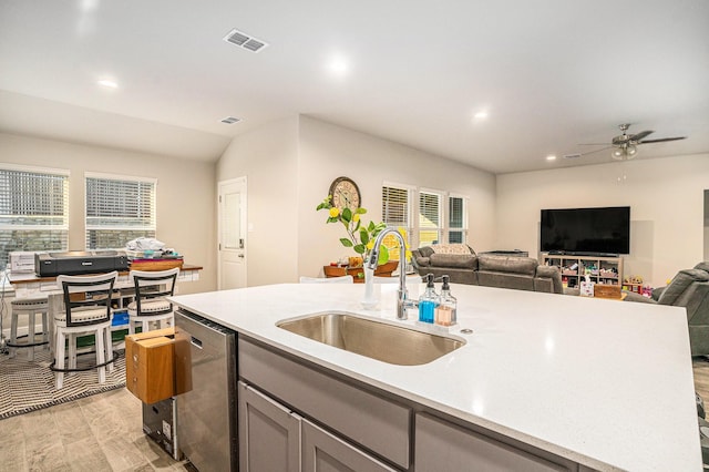 kitchen featuring light countertops, visible vents, stainless steel dishwasher, open floor plan, and a sink