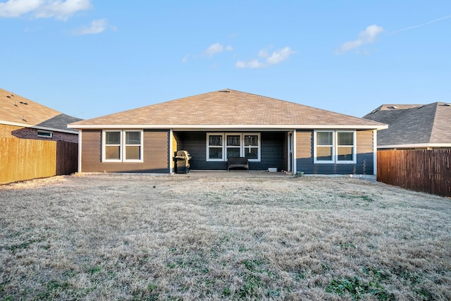 rear view of property with a fenced backyard and a yard