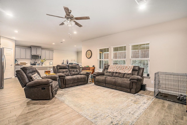 living room with visible vents, baseboards, a ceiling fan, light wood-style floors, and recessed lighting