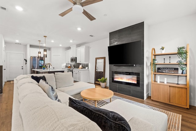 living area featuring recessed lighting, visible vents, a ceiling fan, wood finished floors, and a tile fireplace