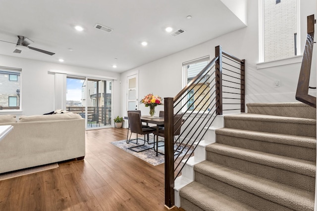 living room featuring stairs, visible vents, and wood finished floors