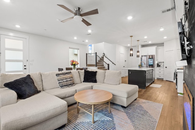 living room featuring light wood-style floors, stairway, visible vents, and recessed lighting