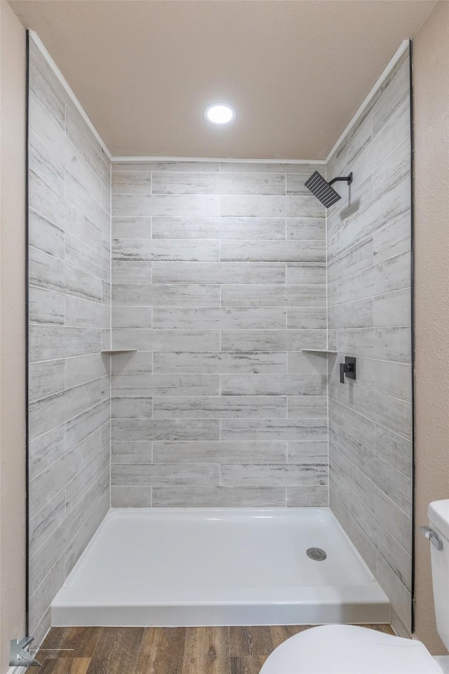 full bath featuring toilet, a stall shower, and wood finished floors