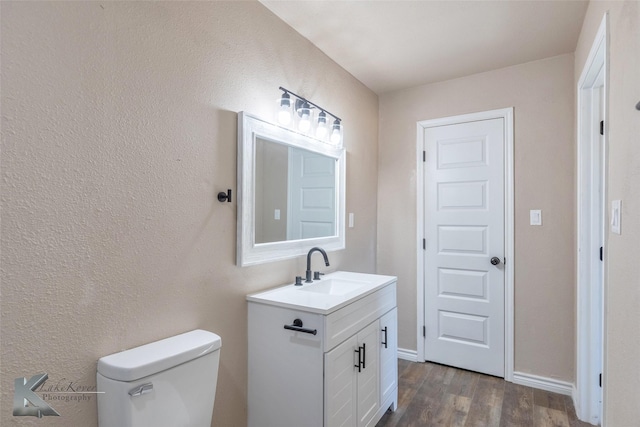 bathroom with baseboards, vanity, toilet, and wood finished floors