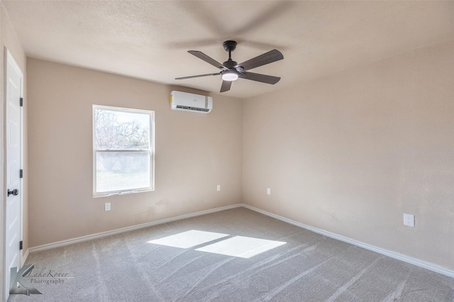 carpeted empty room with a textured ceiling, a wall mounted AC, a ceiling fan, and baseboards