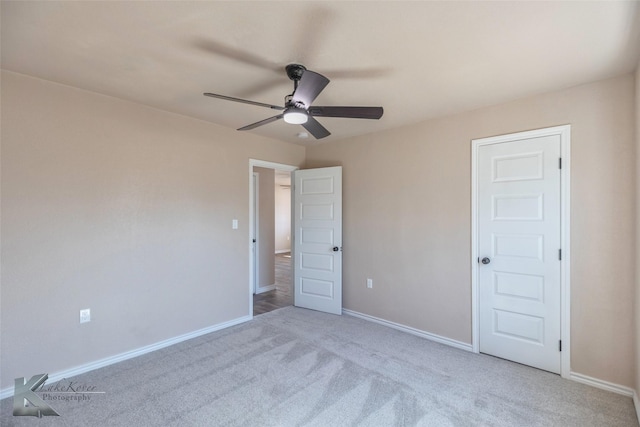 spare room with baseboards, a ceiling fan, and light colored carpet