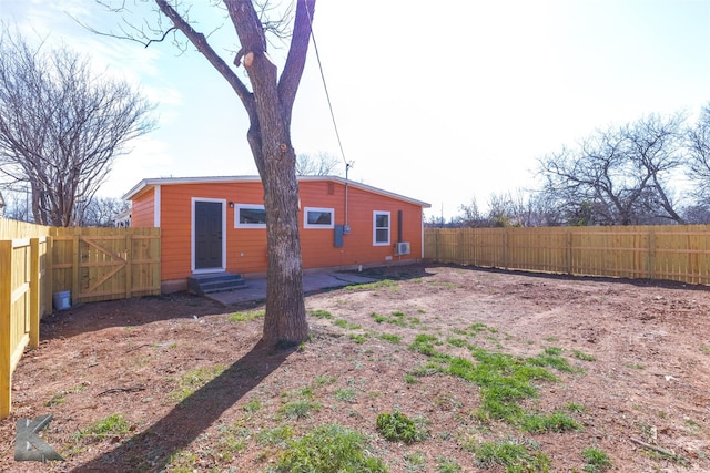 rear view of property featuring entry steps and a fenced backyard