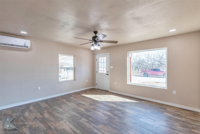 interior space with dark wood-style floors, a wall unit AC, and baseboards