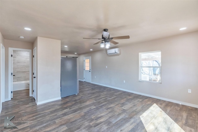 empty room featuring dark wood finished floors, recessed lighting, a wall mounted AC, a barn door, and baseboards