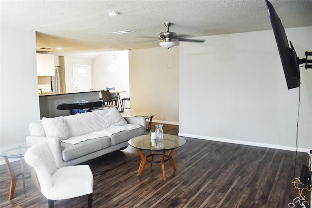 living area featuring a textured ceiling, dark wood finished floors, a ceiling fan, and baseboards