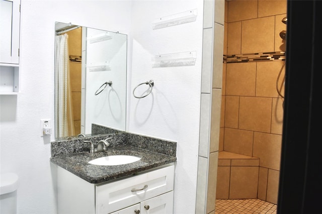 full bathroom featuring toilet, a tile shower, and vanity