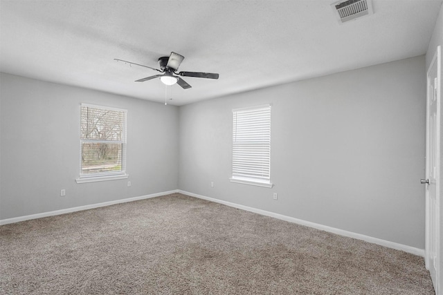 carpeted empty room with baseboards, visible vents, and ceiling fan