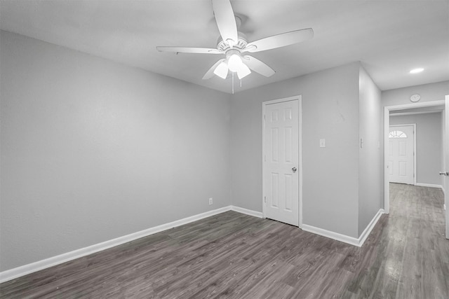 empty room featuring dark wood-style floors, a ceiling fan, and baseboards