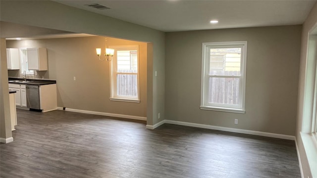 kitchen featuring dark countertops, visible vents, an inviting chandelier, white cabinetry, and a sink