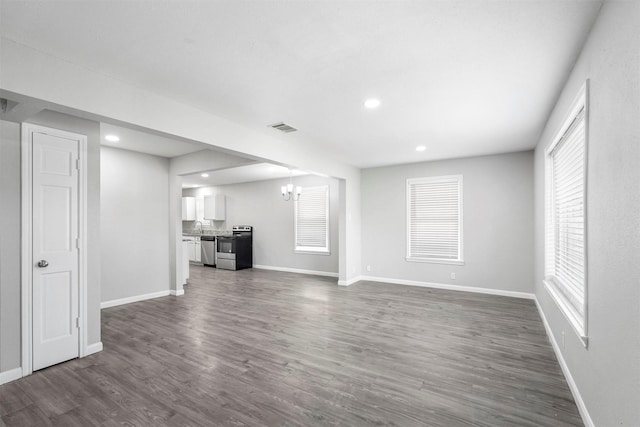 unfurnished living room featuring visible vents, a notable chandelier, recessed lighting, baseboards, and dark wood-style flooring