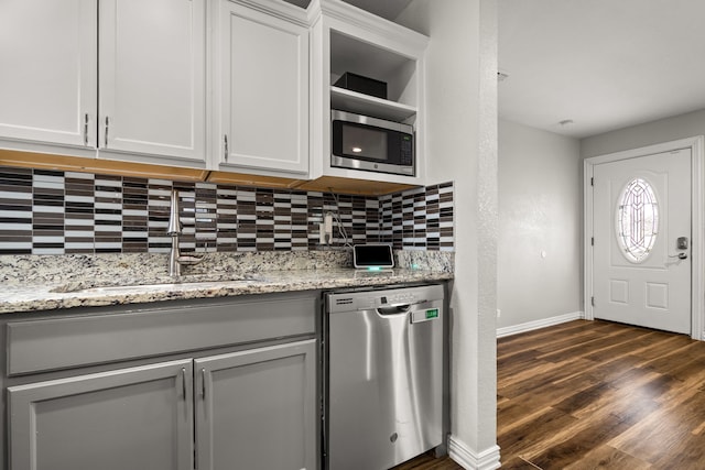 kitchen featuring dark wood-style floors, appliances with stainless steel finishes, white cabinets, a sink, and light stone countertops