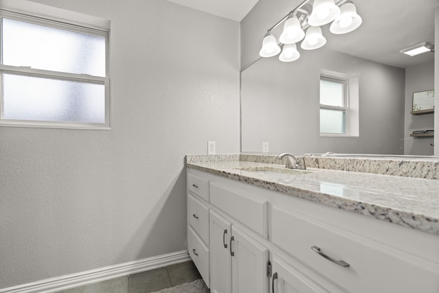 bathroom with a textured wall, tile patterned flooring, baseboards, and vanity