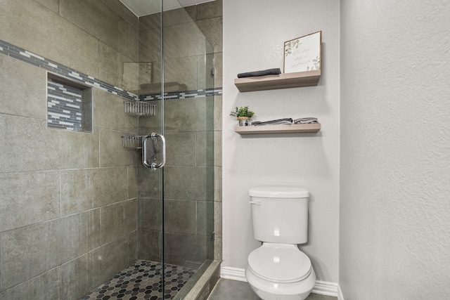 bathroom with toilet, a shower stall, and baseboards