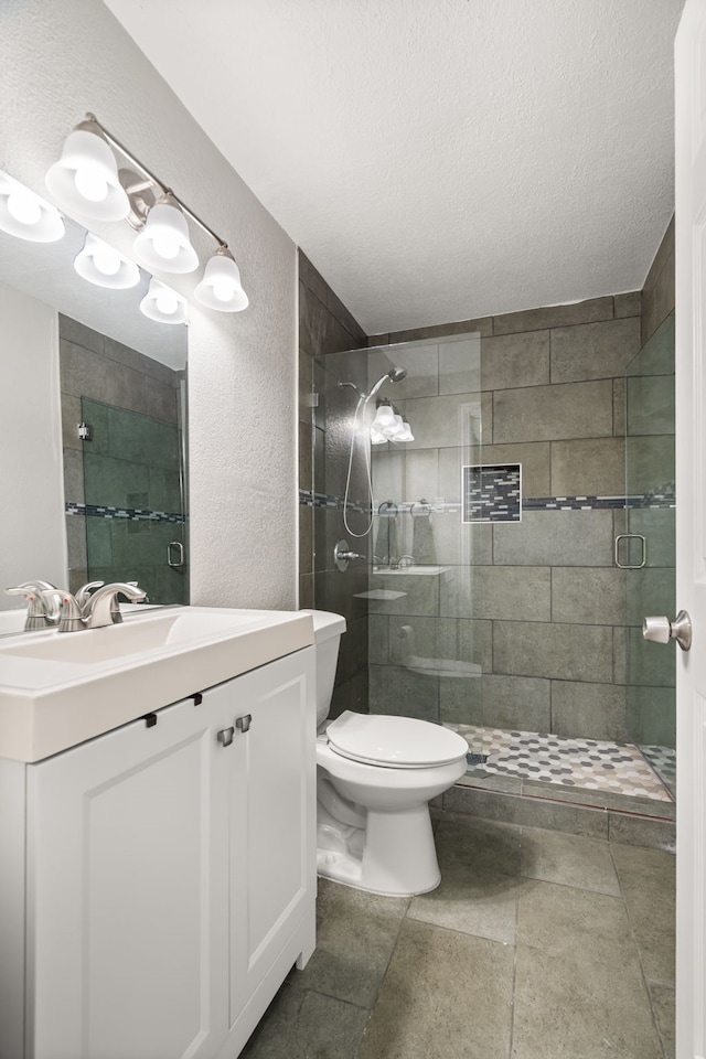 bathroom with a textured wall, toilet, a textured ceiling, vanity, and a shower stall