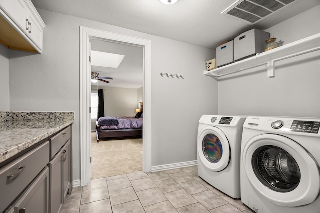 washroom featuring light tile patterned flooring, washing machine and dryer, a skylight, visible vents, and cabinet space