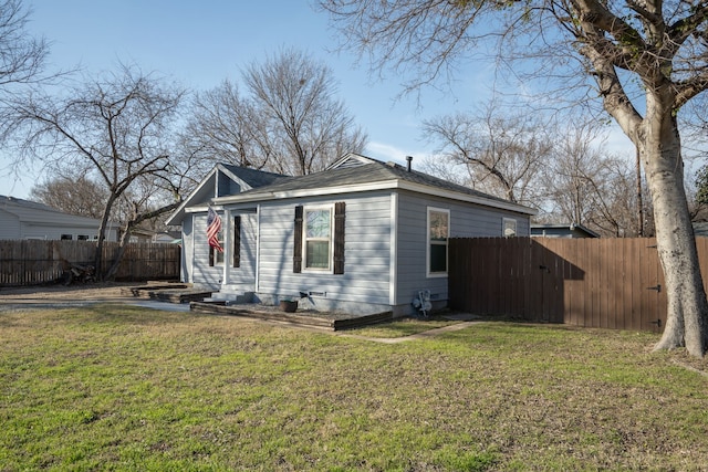 view of side of home with a yard and fence