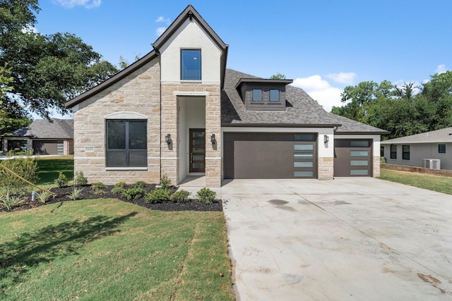 view of front of house with stone siding, a front lawn, a shingled roof, and driveway