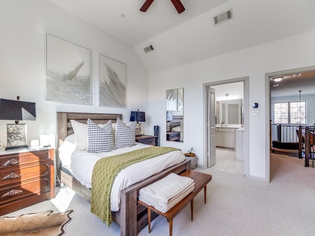 bedroom with ensuite bathroom, visible vents, vaulted ceiling, and light colored carpet