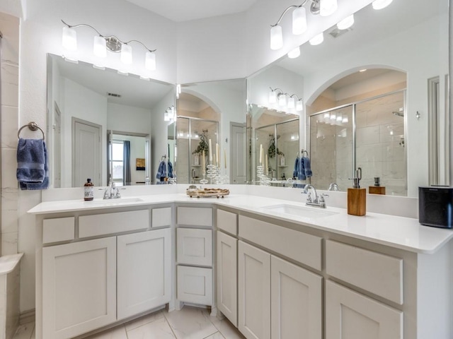 bathroom featuring marble finish floor, a sink, a shower stall, and double vanity