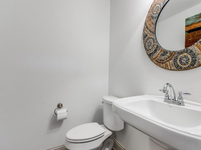 bathroom with toilet, baseboards, and a sink