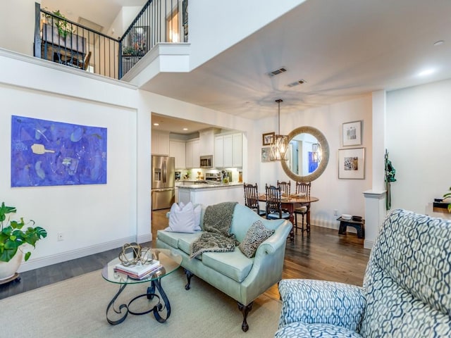 living area with recessed lighting, a notable chandelier, dark wood-type flooring, visible vents, and baseboards