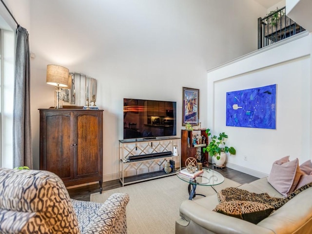 living area with a high ceiling, a fireplace, wood finished floors, and baseboards