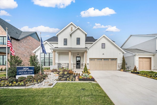 modern farmhouse style home featuring covered porch, board and batten siding, stone siding, driveway, and a front lawn