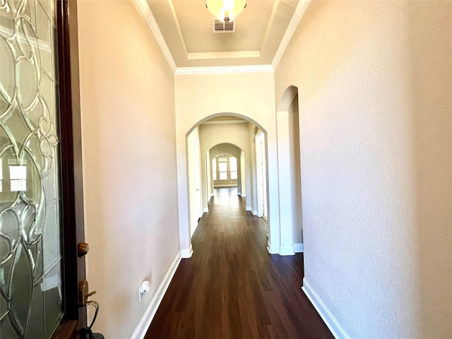 hall with arched walkways, ornamental molding, dark wood-style floors, and baseboards