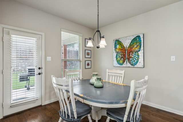 dining space with dark wood-style flooring, baseboards, and an inviting chandelier